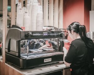 Бариста използва професионална двубойлерна кафемашина Fiamma Compass 2 за приготвяне на еспресо